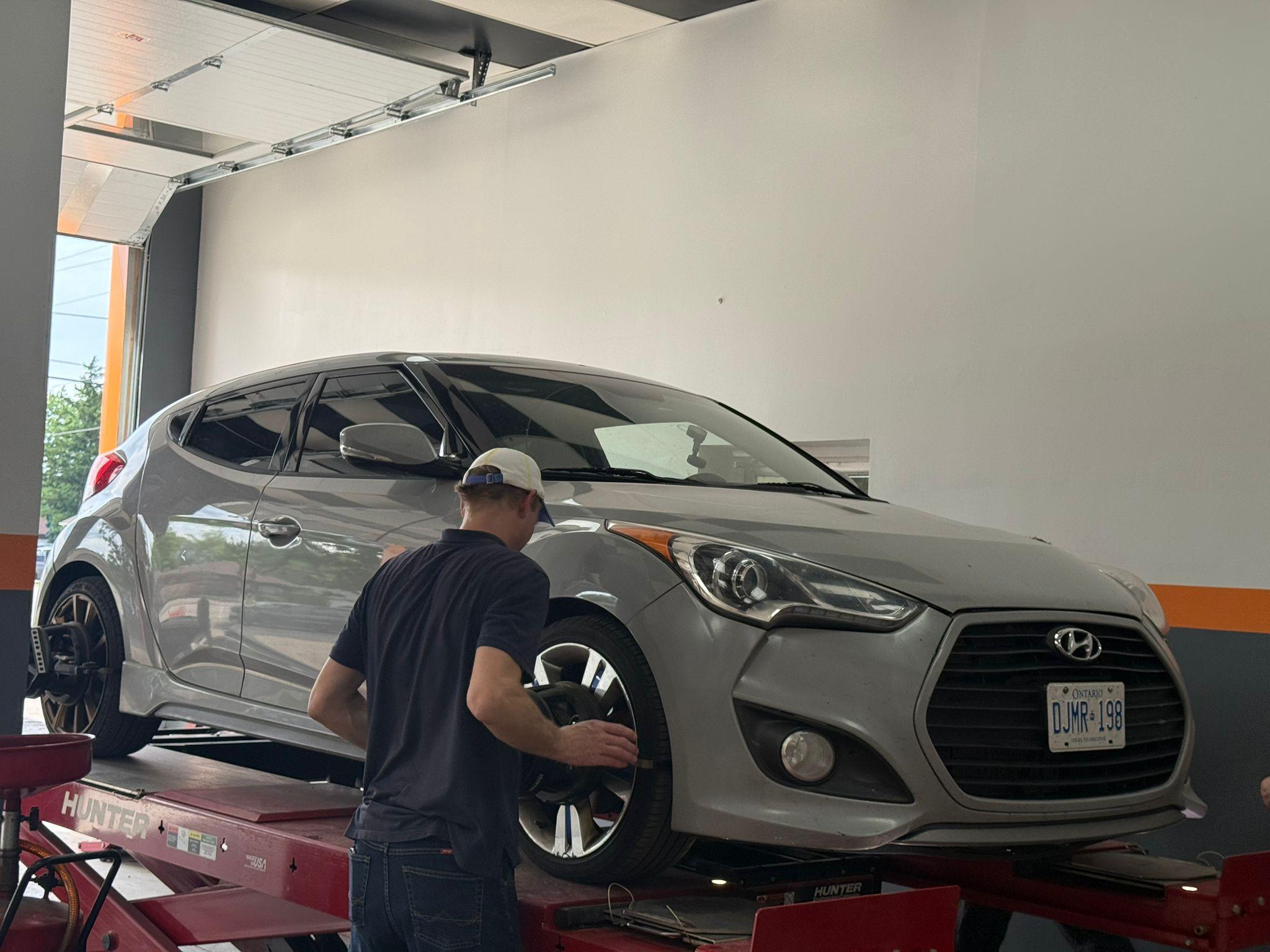 Technician performing a wheel alignment on a Hunter lift